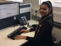 Vanessa trabaja en un ordenador en un escritorio con auriculares puestos